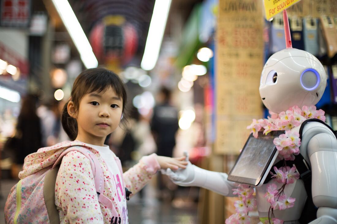 Young girl with left hand on store robot hand.